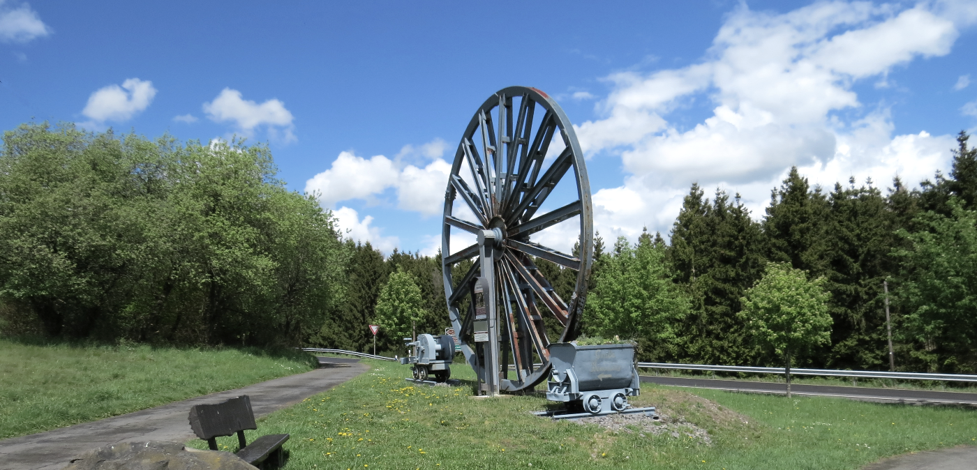 Das Grubenrad mit Lore markiert die Einfahrt zum 3 Stollen Besucherbergwerk Grube Bendisberg bei Langenfeld, © Touristik-Büro Vordereifel/ Svenja Schulze-Entrup