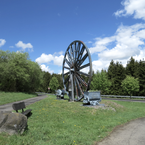 Das Grubenrad mit Lore markiert die Einfahrt zum 3 Stollen Besucherbergwerk Grube Bendisberg bei Langenfeld, © Touristik-Büro Vordereifel/ Svenja Schulze-Entrup